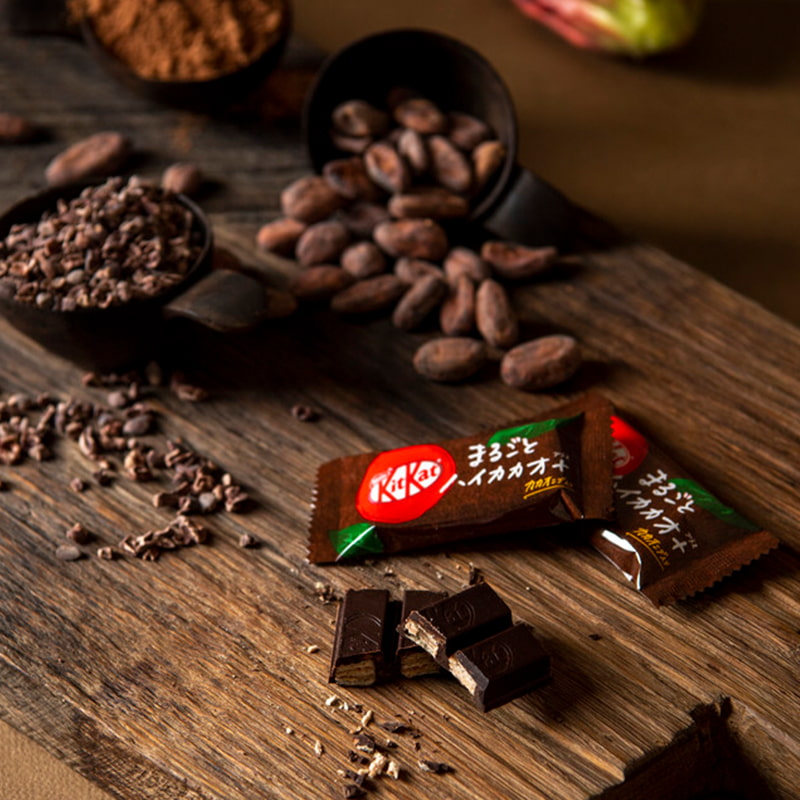 A 72% cacao dark chocolate kitkat on a table with some cacao beans